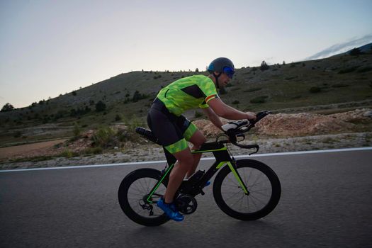 triathlon athlete riding professional racing bike at workout on curvy country road