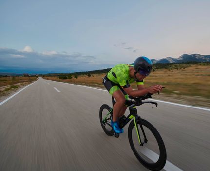 triathlon athlete riding professional racing bike at workout on curvy country road