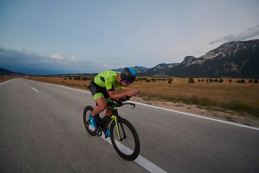 triathlon athlete riding professional racing bike at workout on curvy country road