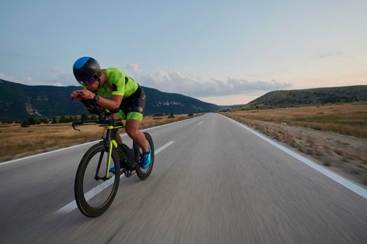 triathlon athlete riding professional racing bike at workout on curvy country road