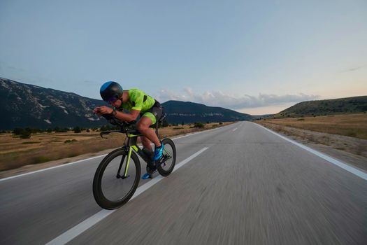 triathlon athlete riding professional racing bike at workout on curvy country road