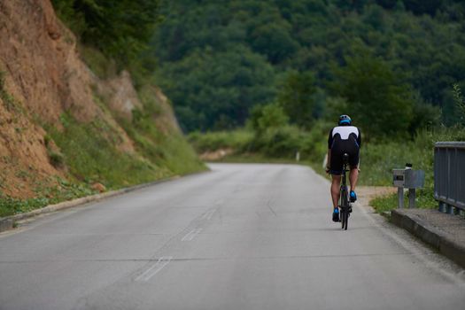 triathlon athlete riding racing bike on morning training wearing black sporty clothes