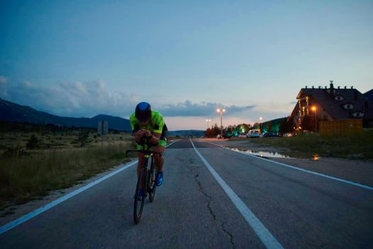 triathlon athlete riding professional racing bike at night workout on curvy country road w