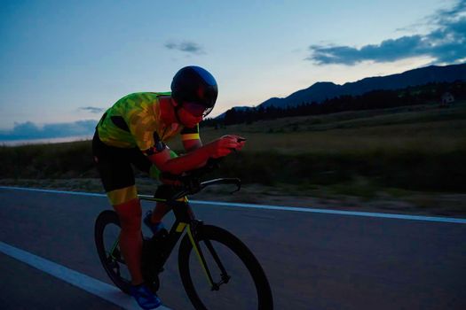 triathlon athlete riding professional racing bike at night workout on curvy country road w