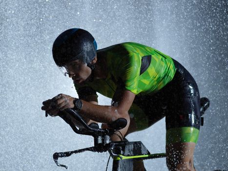 triathlon athlete riding professional racing bike at night with bad weather and falling rain