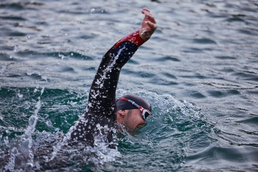 triathlon athlete swimming on beautiful morning sunrise training in lake wearing wetsuit concept of strength and endurance