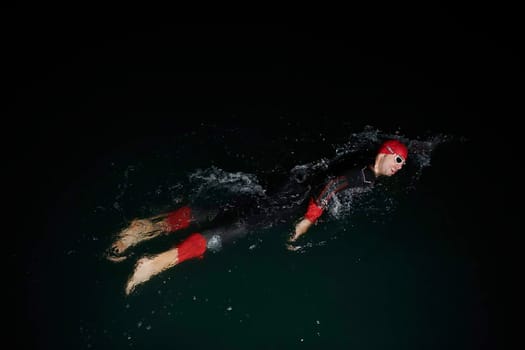 triathlon swimmer have extreme training  on dark night wearing wetsuit concept of strength and endurance