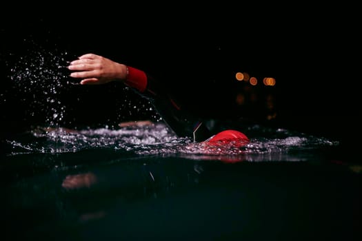 triathlon swimmer have extreme training  on dark night wearing wetsuit concept of strength and endurance