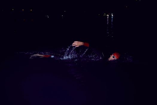 triathlon swimmer have extreme training  on dark night wearing wetsuit concept of strength and endurance