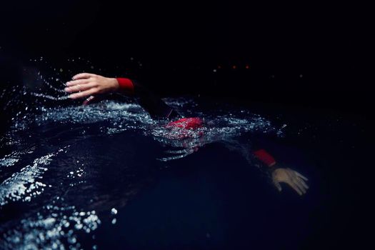 triathlon swimmer have extreme training  on dark night wearing wetsuit concept of strength and endurance