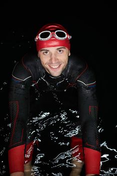 real triathlete swimmer having a break during hard training at lake on dark night