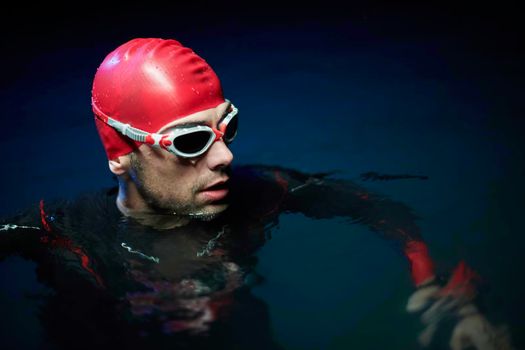 real triathlete swimmer having a break during hard training at lake on dark night