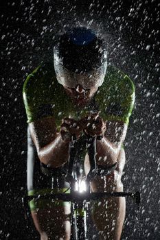 triathlon athlete riding professional racing bike fast  at night with bad weather and falling rain