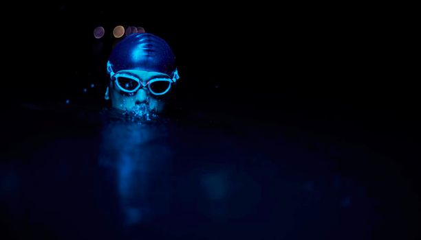 real triathlete swimmer having a break during hard training at lake on dark night neon gel color lights