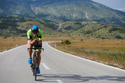 triathlon athlete riding professional racing bike at workout on curvy country road