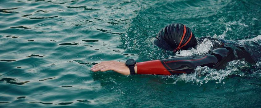 triathlon athlete swimming on beautiful morning sunrise training in lake wearing wetsuit concept of strength and endurance