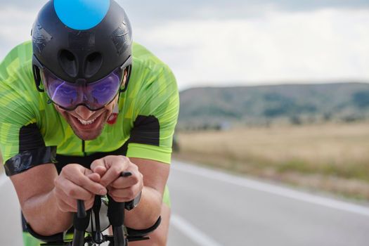 triathlon athlete riding professional racing bike at workout on curvy country road