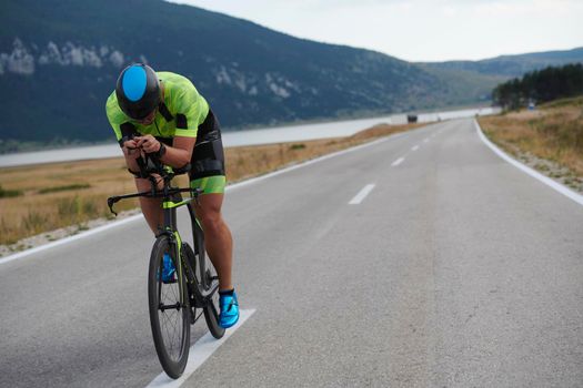 triathlon athlete riding professional racing bike at workout on curvy country road