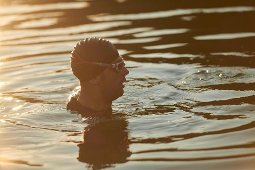 real triathlete swimmer having a break during hard training at lake on beautiful morning