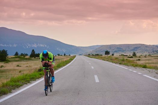 triathlon athlete riding professional racing bike at workout on curvy country road