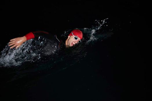 triathlon swimmer have extreme training  on dark night wearing wetsuit concept of strength and endurance