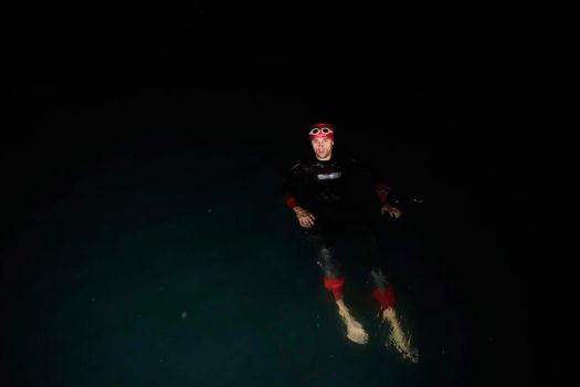 triathlon swimmer have extreme training  on dark night wearing wetsuit concept of strength and endurance