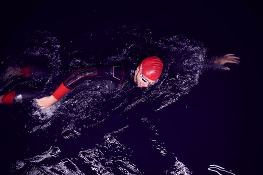 triathlon swimmer have extreme training  on dark night wearing wetsuit concept of strength and endurance