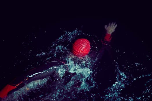 triathlon swimmer have extreme training  on dark night wearing wetsuit concept of strength and endurance