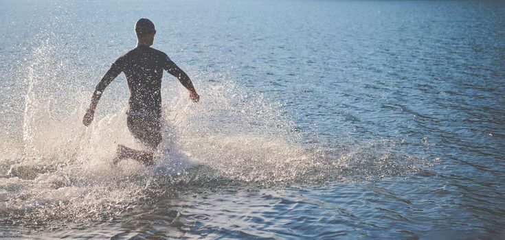 triathlon athlete start swimming training splashing water while running and jumping