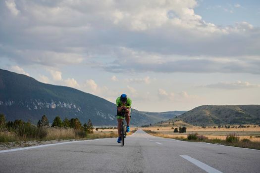 triathlon athlete riding professional racing bike at workout on curvy country road