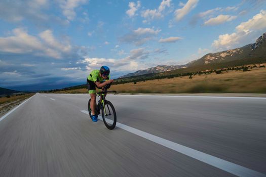 triathlon athlete riding professional racing bike at workout on curvy country road