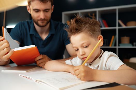 Father helping his little son with school homework close up