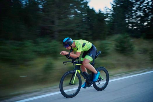 triathlon athlete riding professional racing bike at night workout on curvy country road w