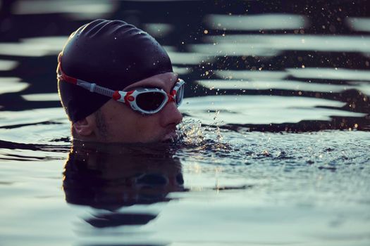 real triathlete swimmer having a break during hard training at lake on beautiful morning