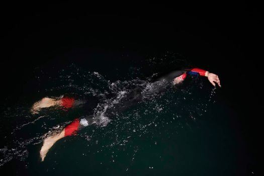 triathlon swimmer have extreme training  on dark night wearing wetsuit concept of strength and endurance