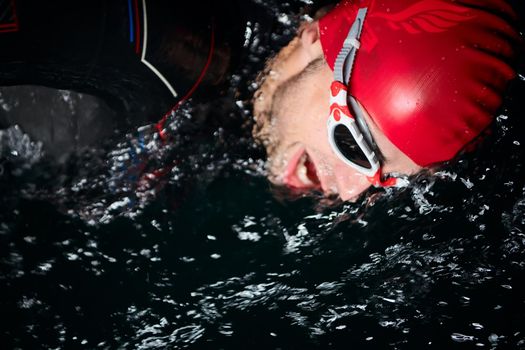 triathlon swimmer have extreme training  on dark night wearing wetsuit concept of strength and endurance