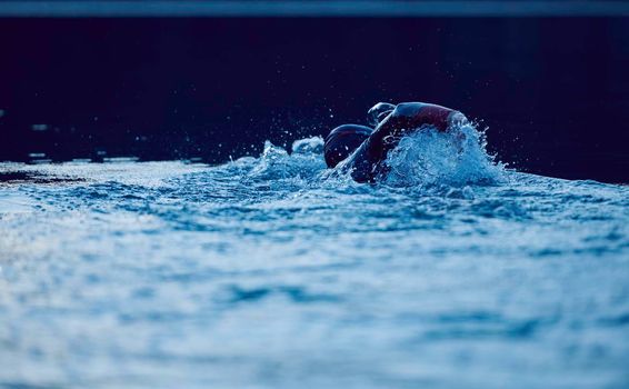 triathlon athlete swimming on beautiful morning sunrise training in lake wearing wetsuit concept of strength and endurance