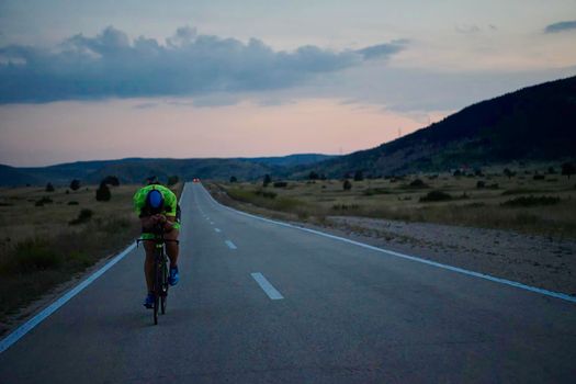 triathlon athlete riding professional racing bike at night workout on curvy country road w