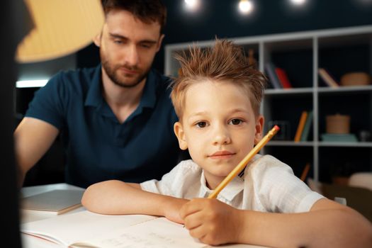 Dad and son doing school homework together sitting at the table