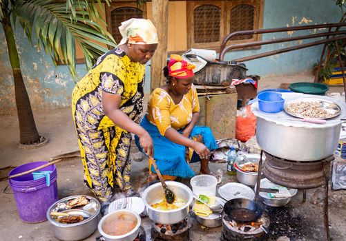 African woman cooking traditional food at street