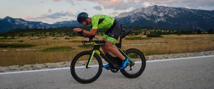 triathlon athlete riding professional racing bike at workout on curvy country road