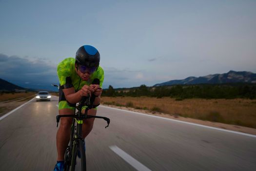 triathlon athlete riding professional racing bike at workout on curvy country road