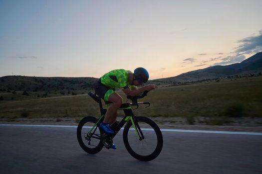 triathlon athlete riding professional racing bike at workout on curvy country road