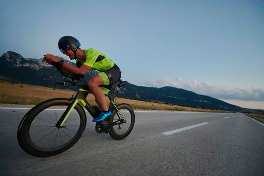 triathlon athlete riding professional racing bike at workout on curvy country road