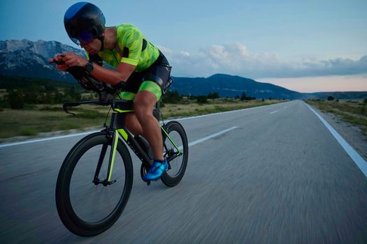 triathlon athlete riding professional racing bike at night workout on curvy country road w