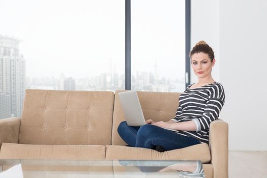 beautiful young woman on sofa at home websurfing  internet with laptop computer