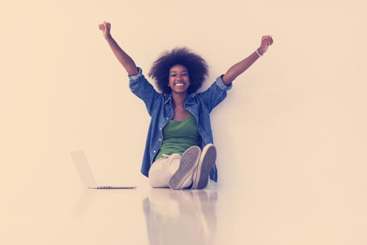 Portrait of happy young african american woman sitting on floor with laptop