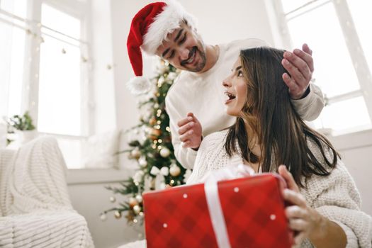 Young cheerful couple in love with present for Christmas, portrait