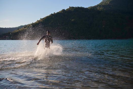 triathlon athlete start swimming training splashing water while running and jumping