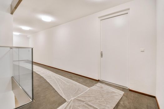Wide corridor with white walls and brown floors